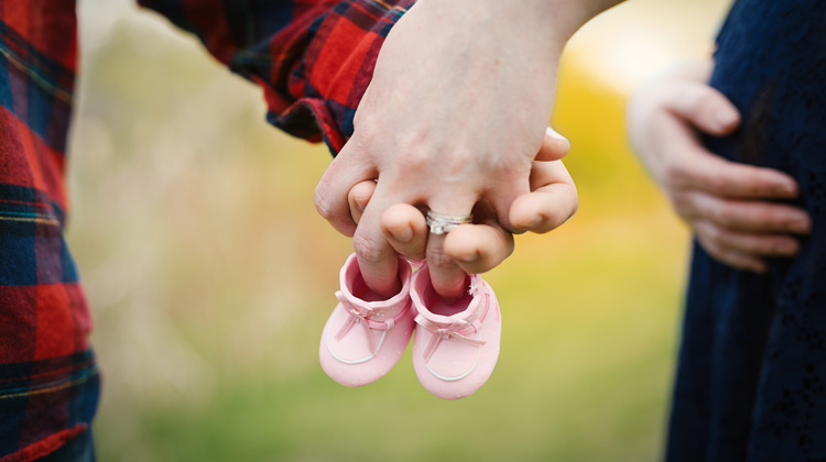 Couple holding baby shoes